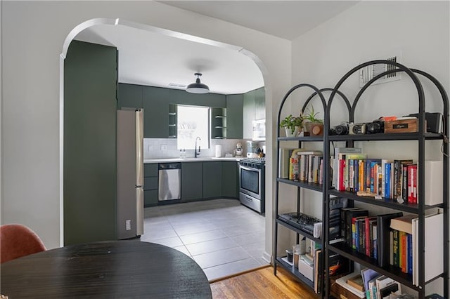 831 E 25th Ave, North Kansas City, MO 64116 - kitchen featuring stainless steel appliances, arched walkways, a sink, and light countertops