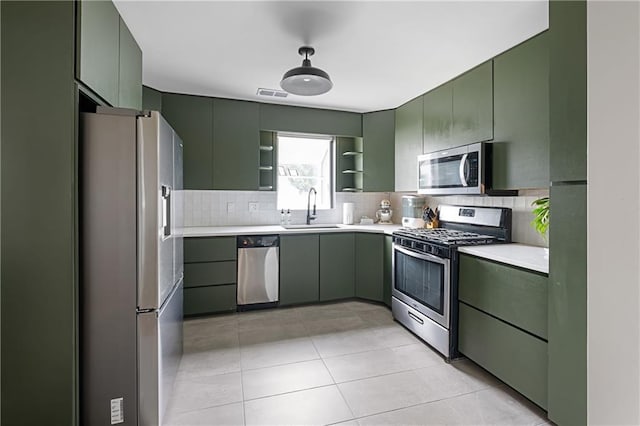 831 E 25th Ave, North Kansas City, MO 64116 - kitchen with stainless steel appliances, green cabinets, a sink, open shelves, and light countertops