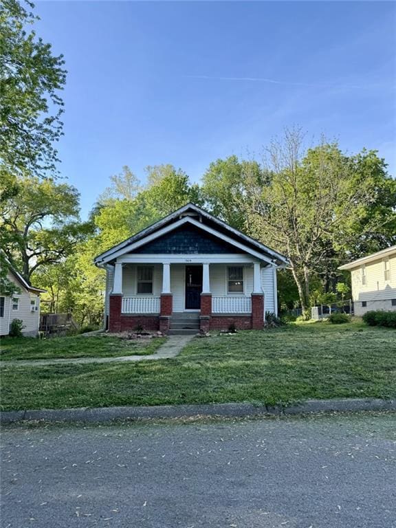 bungalow-style home featuring covered porch and a front lawn