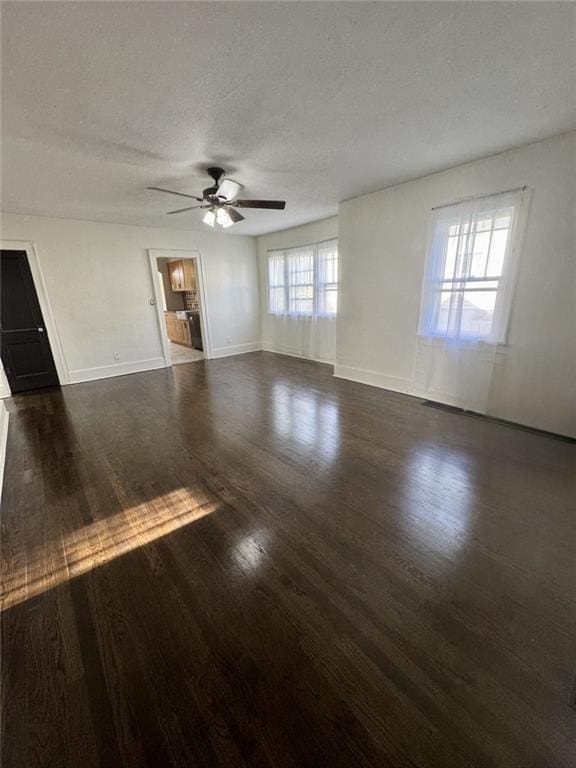 unfurnished living room featuring ceiling fan, dark wood-style floors, baseboards, and a textured ceiling