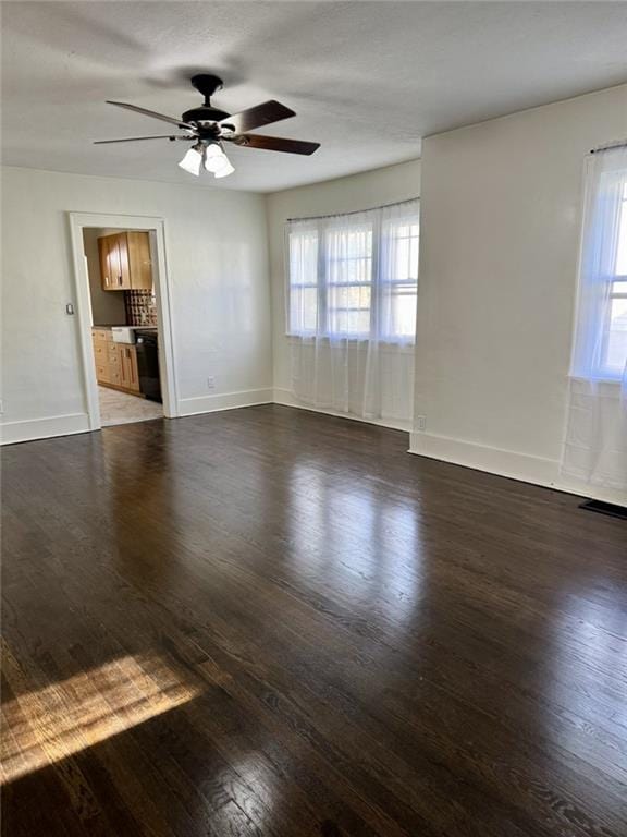 unfurnished living room featuring ceiling fan, dark wood-style flooring, and baseboards