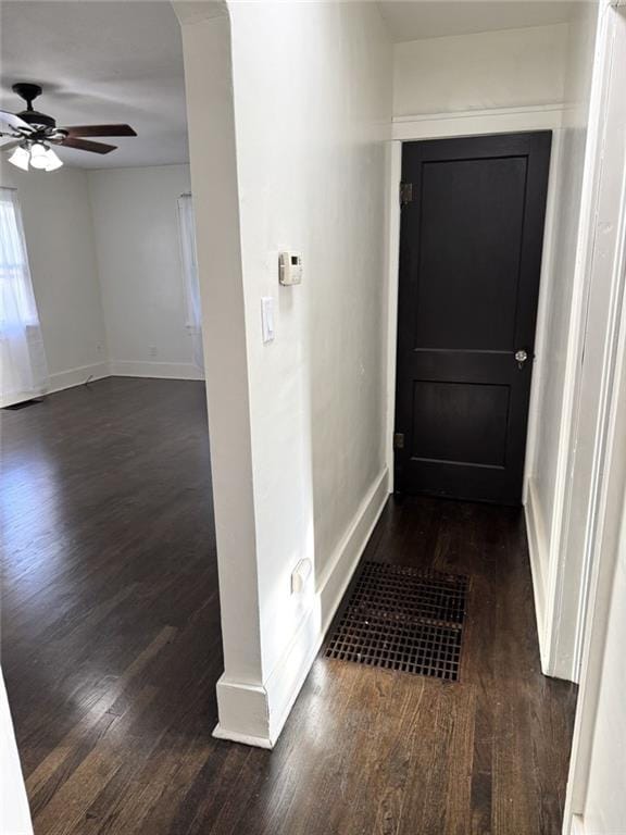 hallway with dark wood-style flooring and baseboards