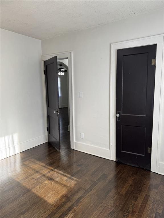 spare room featuring baseboards, wood finished floors, and a textured ceiling