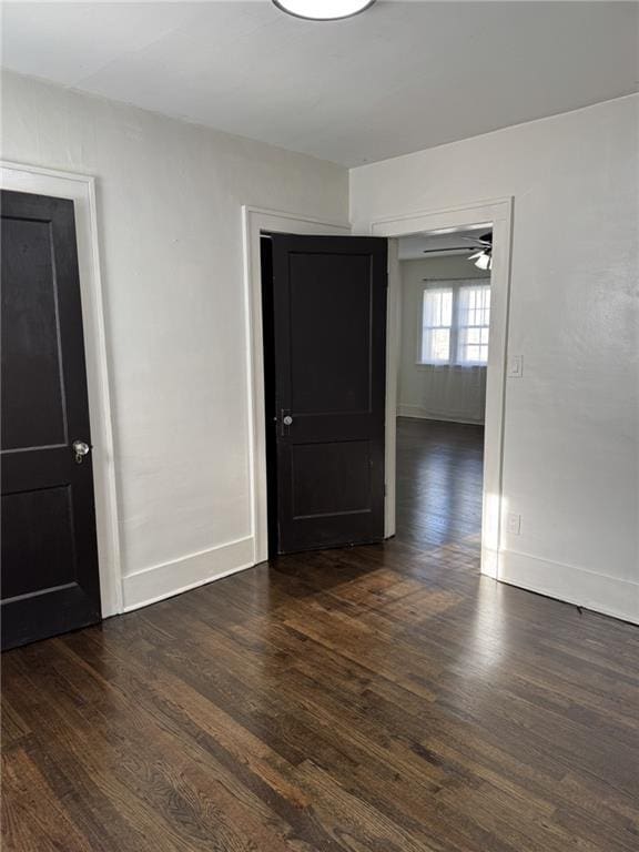 empty room with dark wood-type flooring and baseboards