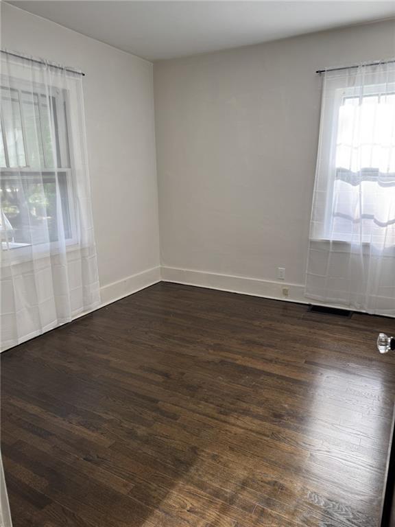 spare room featuring dark wood finished floors and baseboards