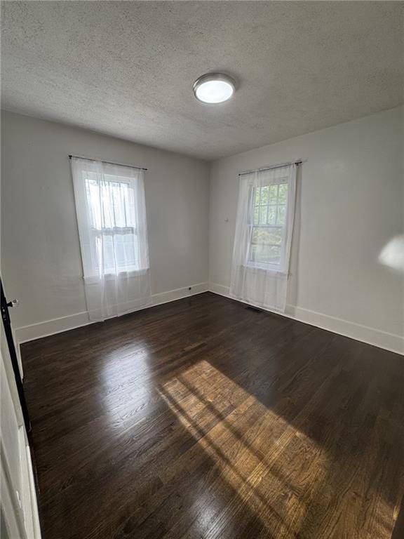 spare room with dark wood-style floors, baseboards, and a textured ceiling