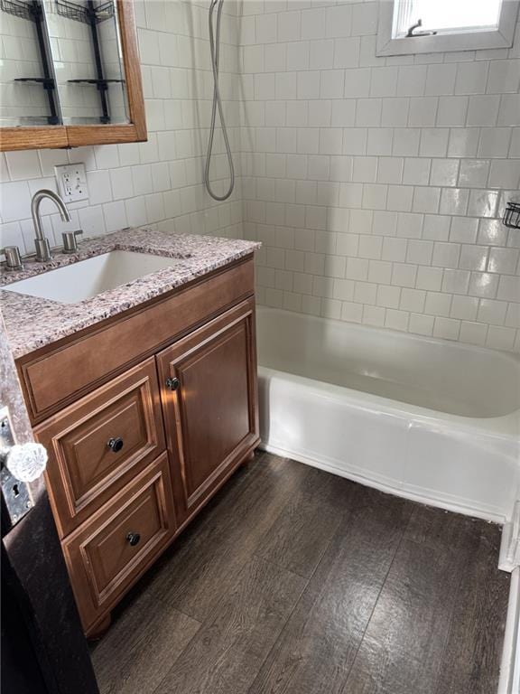 bathroom featuring wood finished floors, shower / tub combination, tile walls, and vanity