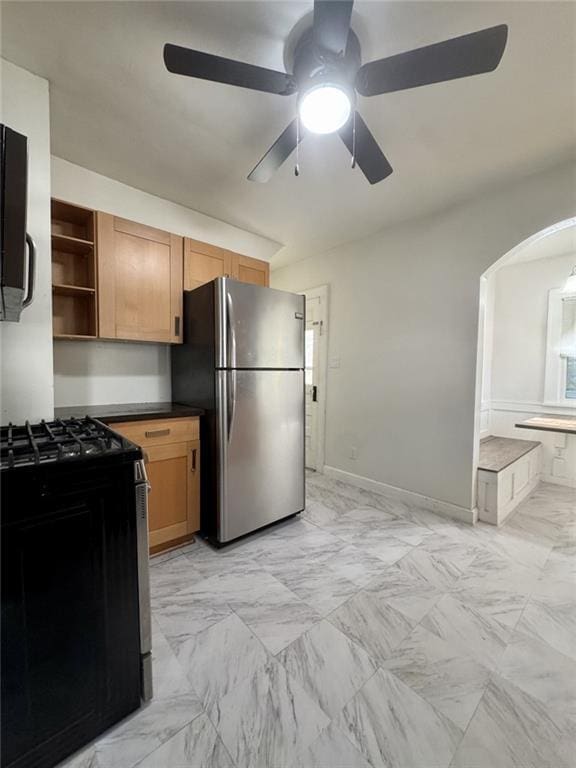 kitchen with freestanding refrigerator, gas range, open shelves, a ceiling fan, and light marble finish floors