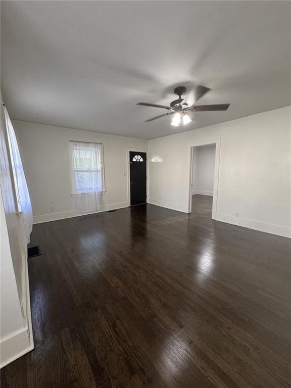 unfurnished living room featuring dark wood-style flooring, a ceiling fan, and baseboards