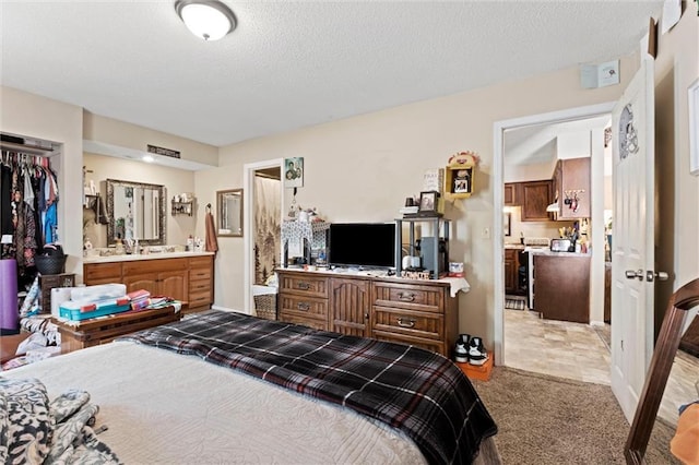 bedroom with light carpet, a textured ceiling, and ensuite bathroom