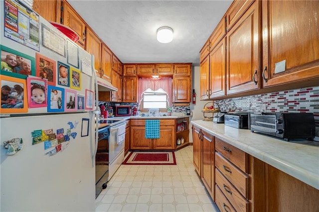 603 W 30th St, Higginsville, MO 64037 - kitchen with white appliances, light countertops, light floors, brown cabinetry, and under cabinet range hood