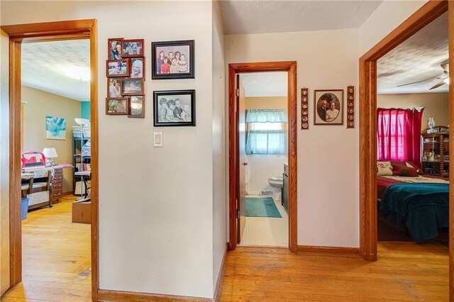 603 W 30th St, Higginsville, MO 64037 - corridor with light wood-type flooring, baseboards, a textured ceiling, and a desk