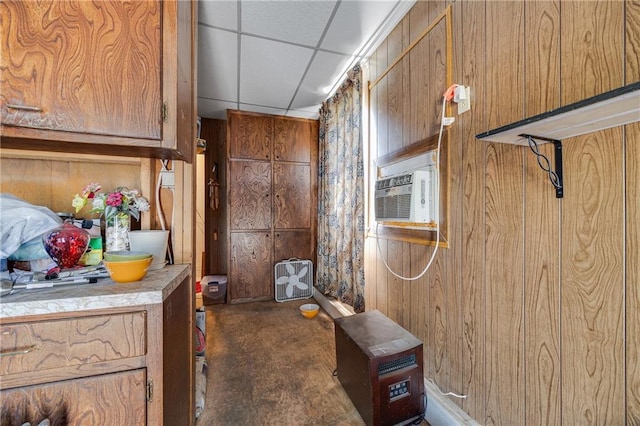 603 W 30th St, Higginsville, MO 64037 - kitchen featuring brown cabinetry, light countertops, wood walls, and a paneled ceiling