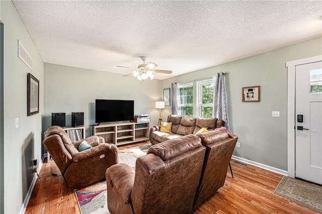 living room featuring wood finished floors, a textured ceiling, ceiling fan, and baseboards