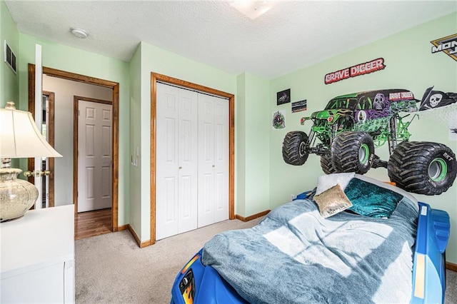 bedroom featuring light colored carpet, a closet, baseboards, and a textured ceiling