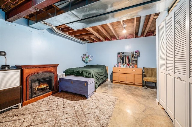 bedroom with concrete flooring and a warm lit fireplace