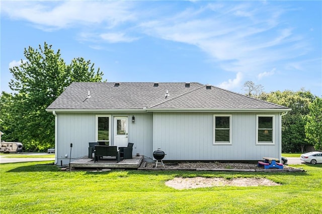 back of property featuring a wooden deck, a lawn, and roof with shingles