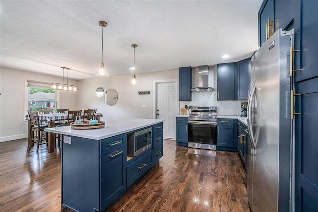 kitchen with stainless steel appliances, blue cabinets, wall chimney range hood, and decorative backsplash