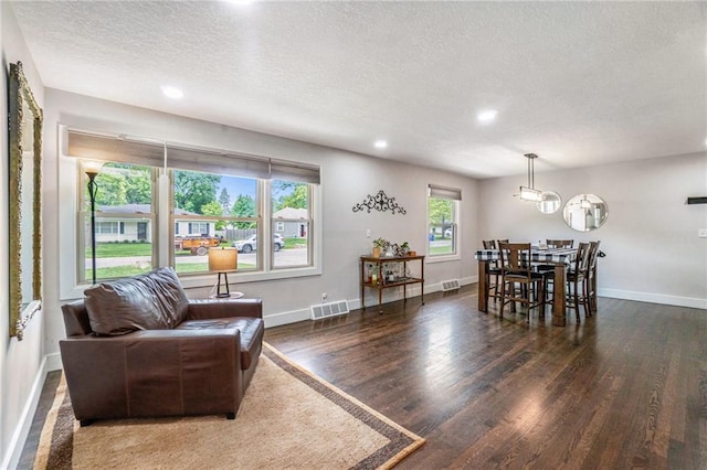 living area featuring a textured ceiling, wood finished floors, recessed lighting, baseboards, and a chandelier