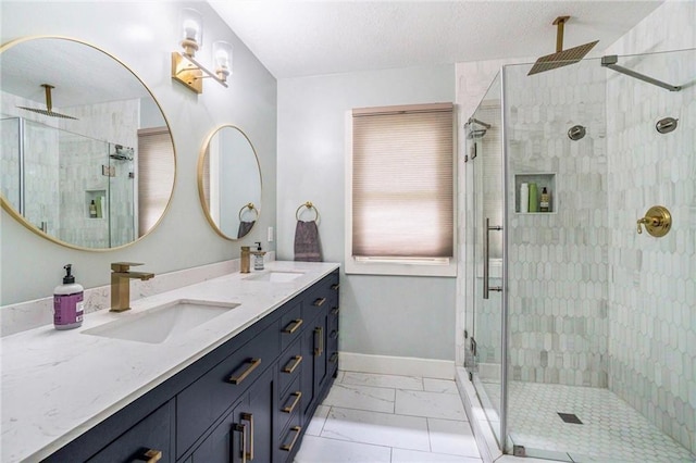 bathroom with a stall shower, baseboards, double vanity, and marble look tiles