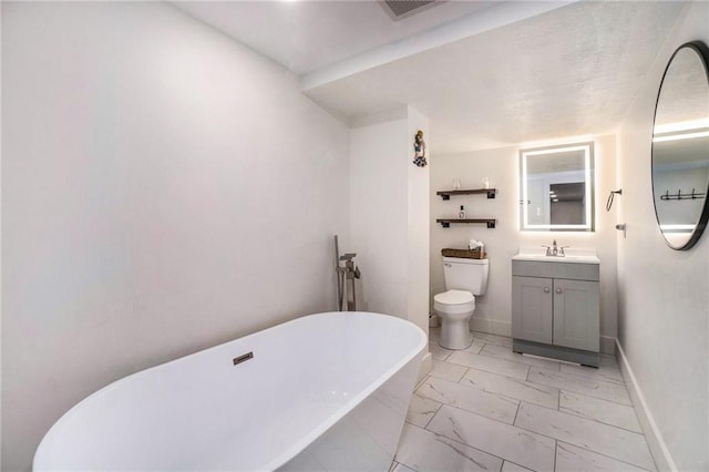 bathroom with marble look tiles, a freestanding tub, toilet, vanity, and baseboards