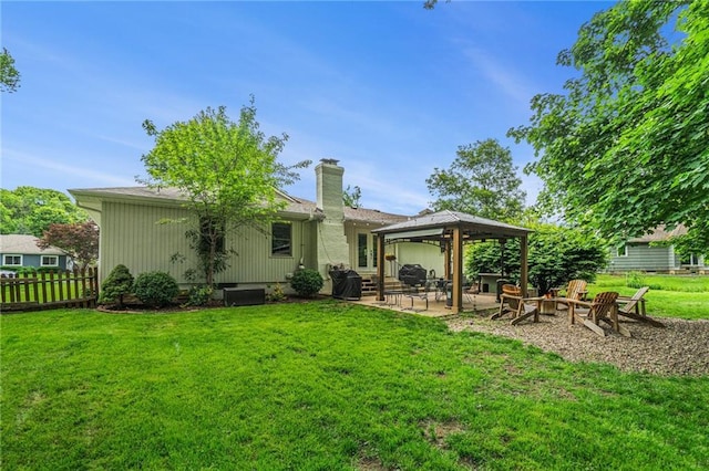 rear view of property featuring a gazebo, a patio, a chimney, and a fire pit