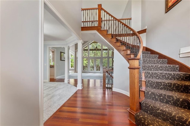 8129 Clearwater Pt, Parkville, MO 64152 - entrance foyer featuring wood finished floors, ornate columns, ornamental molding, stairway, and a towering ceiling