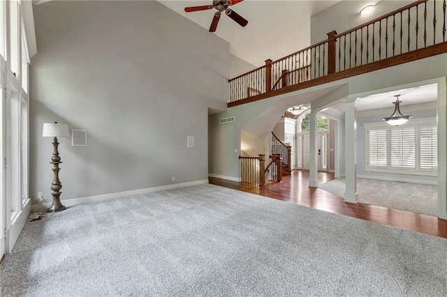 8129 Clearwater Pt, Parkville, MO 64152 - unfurnished living room featuring carpet flooring, a ceiling fan, arched walkways, a high ceiling, and stairway