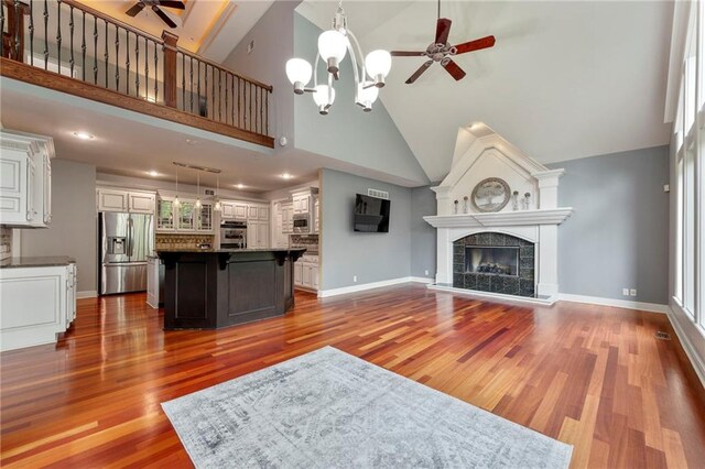 8129 Clearwater Pt, Parkville, MO 64152 - unfurnished living room featuring ceiling fan, wood finished floors, high vaulted ceiling, a chandelier, and a tile fireplace