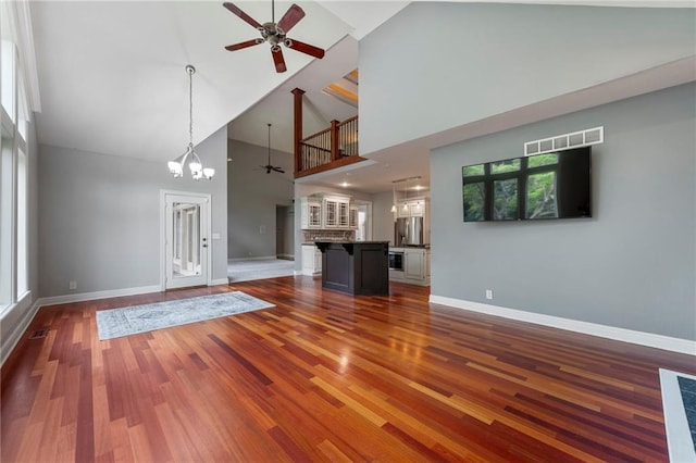 8129 Clearwater Pt, Parkville, MO 64152 - unfurnished living room featuring a ceiling fan, high vaulted ceiling, wood finished floors, and a chandelier