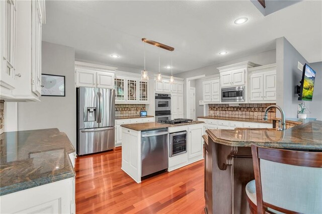 8129 Clearwater Pt, Parkville, MO 64152 - kitchen featuring appliances with stainless steel finishes, wine cooler, light wood-type flooring, decorative backsplash, and recessed lighting