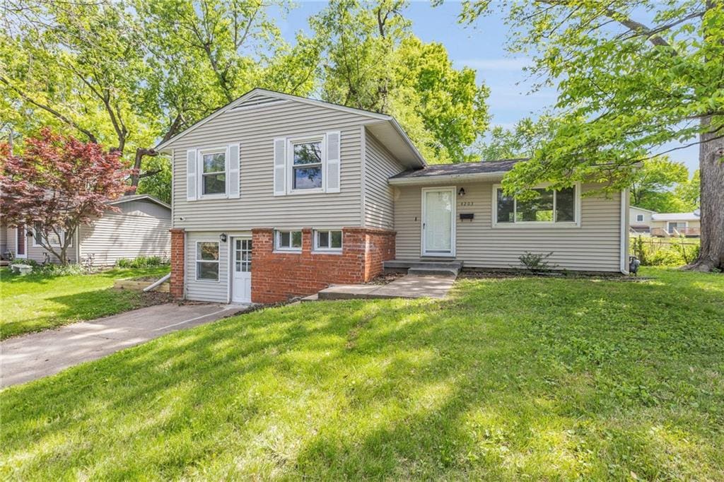 tri-level home with brick siding and a front yard