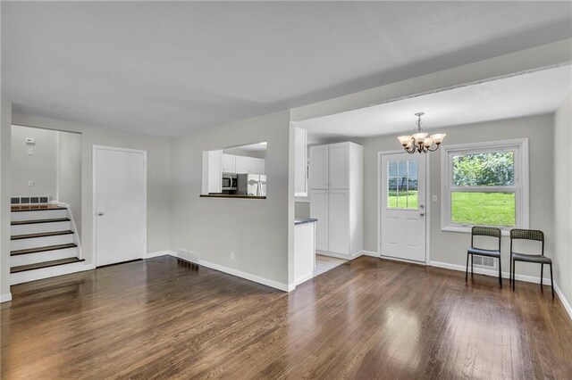 4203 E 113th St, Kansas City, MO 64137 - foyer entrance with a chandelier, dark wood finished floors, baseboards, and stairs