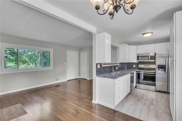 4203 E 113th St, Kansas City, MO 64137 - kitchen featuring appliances with stainless steel finishes, a sink, a chandelier, white cabinets, and dark stone counters