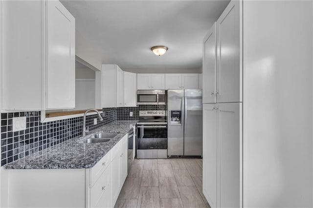 4203 E 113th St, Kansas City, MO 64137 - kitchen with stainless steel appliances, a sink, white cabinets, dark stone countertops, and backsplash