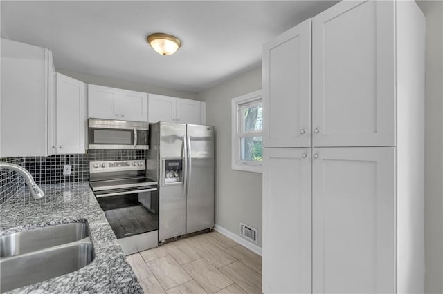 4203 E 113th St, Kansas City, MO 64137 - kitchen featuring stainless steel appliances, a sink, white cabinets, baseboards, and backsplash