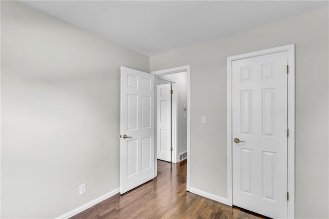 4203 E 113th St, Kansas City, MO 64137 - unfurnished bedroom featuring baseboards and dark wood-type flooring