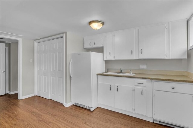 4203 E 113th St, Kansas City, MO 64137 - kitchen with freestanding refrigerator, a sink, light wood-style floors, white cabinetry, and baseboards