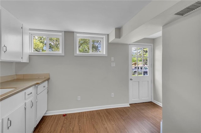 4203 E 113th St, Kansas City, MO 64137 - kitchen featuring wood finished floors, baseboards, white cabinets, and light countertops