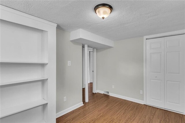 4203 E 113th St, Kansas City, MO 64137 - finished basement with wood finished floors, a textured ceiling, and baseboards