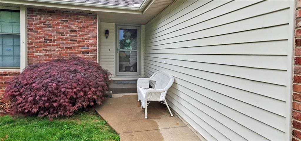 214 Johnston Pkwy, Raymore, MO 64083 - doorway to property featuring brick siding and roof with shingles