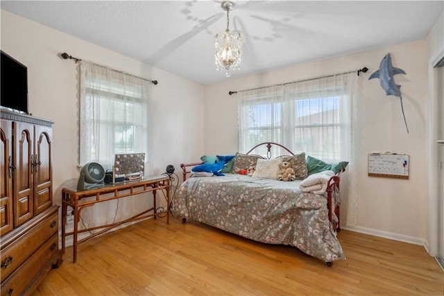 2113 N 155th St, Basehor, KS 66007 - bedroom featuring light wood-style floors, a chandelier, multiple windows, and baseboards