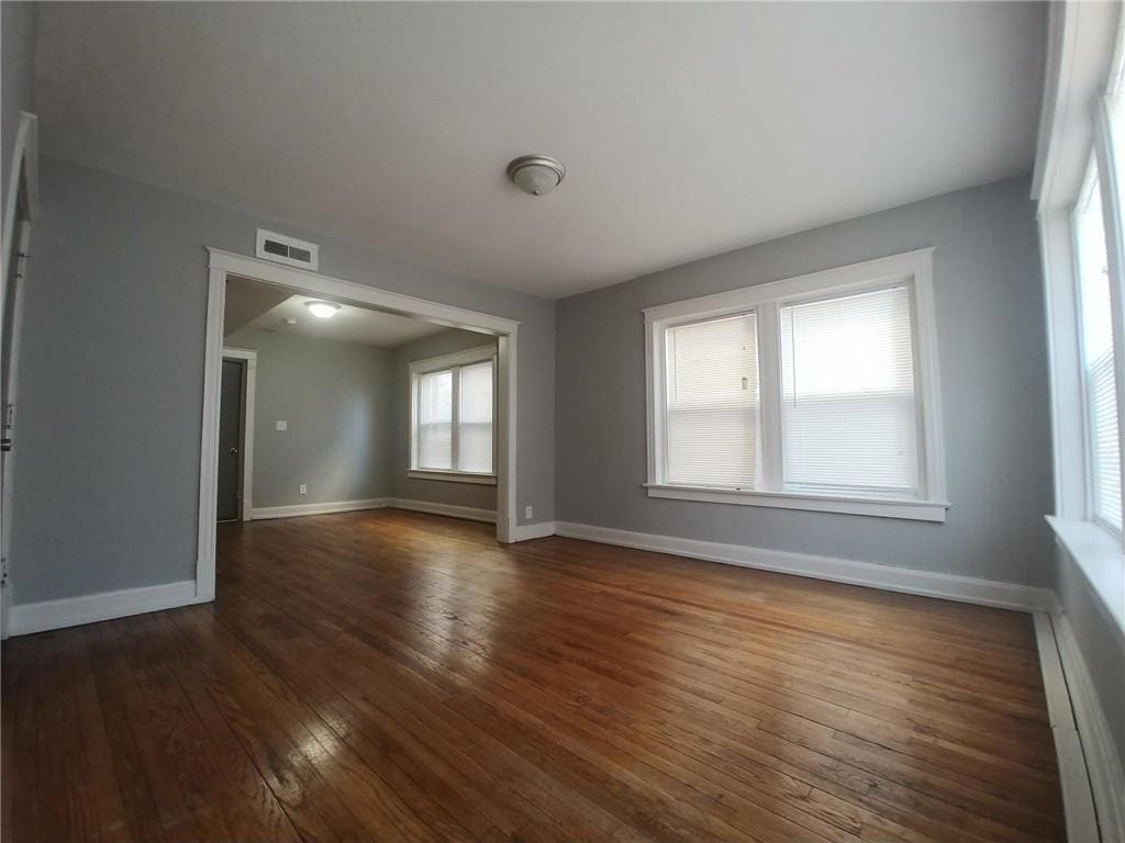 2708 Benton Blvd, Kansas City, MO 64128 - empty room featuring wood-type flooring, a baseboard radiator, and baseboards