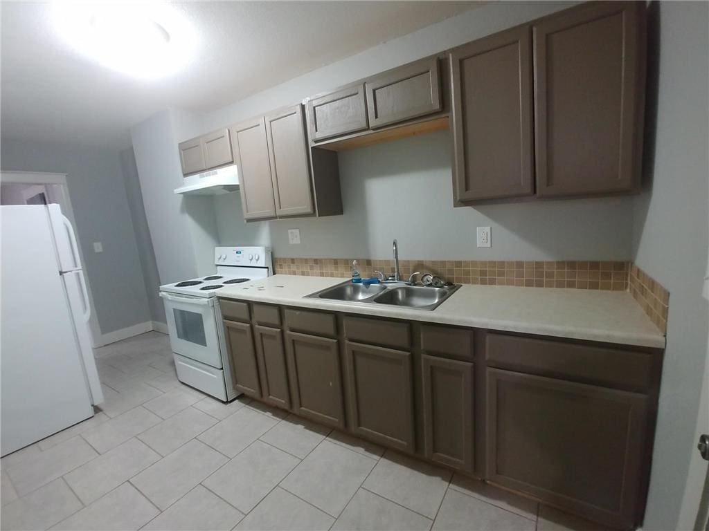 2708 Benton Blvd, Kansas City, MO 64128 - kitchen featuring white appliances, a sink, under cabinet range hood, light countertops, and light tile patterned floors