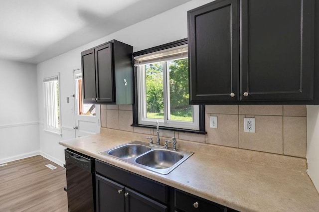2729 S 52nd St, Kansas City, KS 66106 - kitchen featuring black dishwasher, a sink, light countertops, light wood-type flooring, and tasteful backsplash