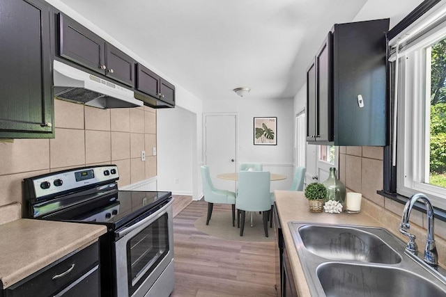 2729 S 52nd St, Kansas City, KS 66106 - kitchen featuring stainless steel electric range oven, a sink, under cabinet range hood, and plenty of natural light