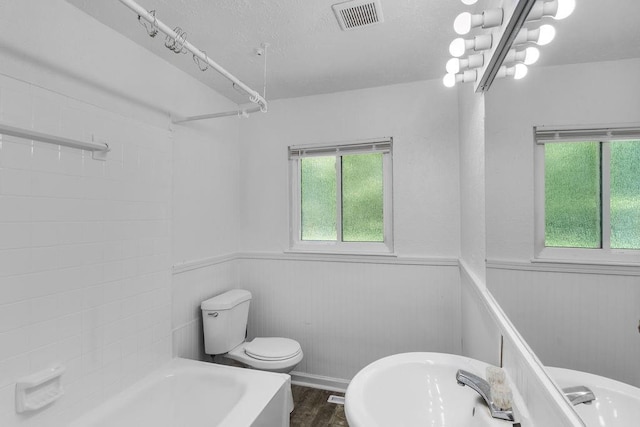 2729 S 52nd St, Kansas City, KS 66106 - full bath with toilet, wainscoting, wood finished floors, shower / washtub combination, and a textured ceiling
