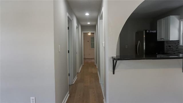2243 Spruce Ave, Kansas City, MO 64127 - kitchen with freestanding refrigerator, dark countertops, light wood finished floors, tasteful backsplash, and arched walkways