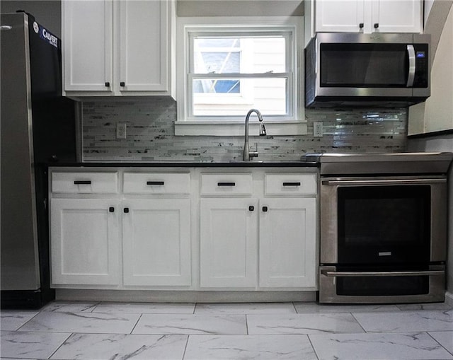 2243 Spruce Ave, Kansas City, MO 64127 - kitchen with appliances with stainless steel finishes, light marble finish floors, white cabinets, and dark countertops