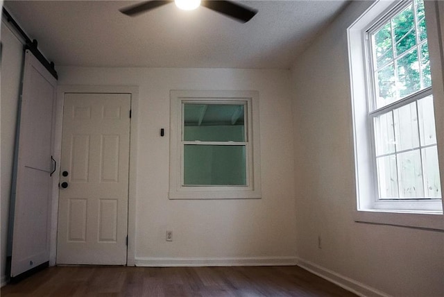 2243 Spruce Ave, Kansas City, MO 64127 - spare room featuring a ceiling fan, dark wood-type flooring, baseboards, and a barn door